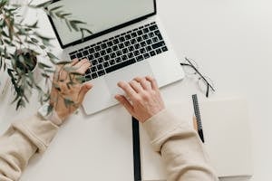 Person in Beige Long Sleeve Shirt Using Macbook Pro